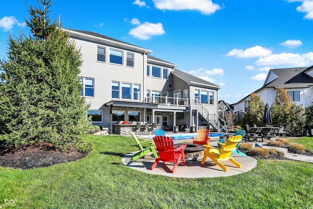 rear view of property featuring a fire pit, a patio area, and a yard