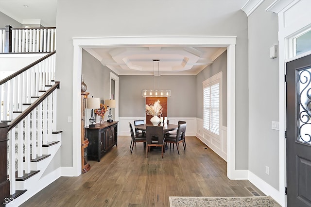 dining space featuring ornamental molding, coffered ceiling, a notable chandelier, beamed ceiling, and dark hardwood / wood-style floors