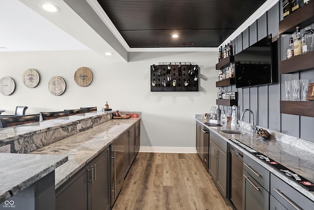 kitchen featuring sink, light hardwood / wood-style flooring, stainless steel dishwasher, and light stone counters