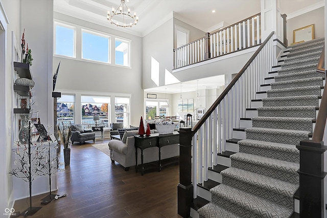 living room featuring dark hardwood / wood-style floors, a towering ceiling, ornamental molding, and a wealth of natural light