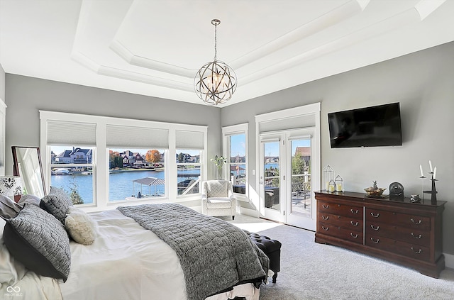 carpeted bedroom with french doors, a raised ceiling, a chandelier, access to outside, and a water view