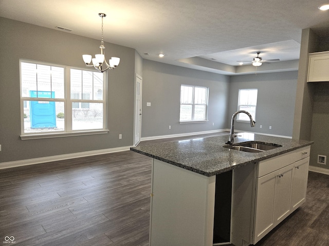 kitchen with sink, a center island with sink, white cabinets, and dark stone countertops