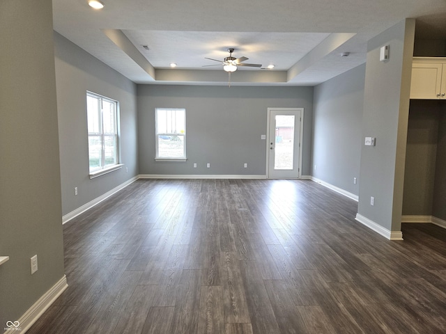 spare room with ceiling fan, a raised ceiling, and dark hardwood / wood-style flooring