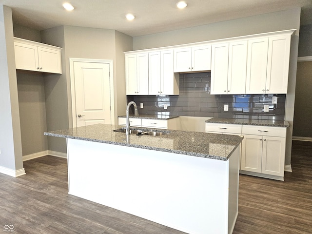 kitchen featuring white cabinetry, dark stone countertops, sink, dark hardwood / wood-style floors, and a center island with sink