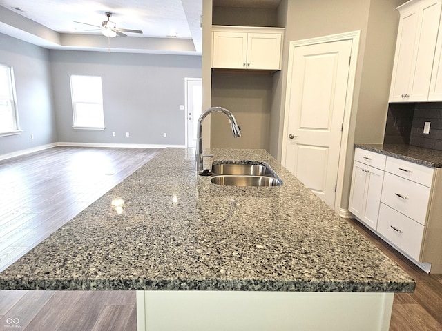 kitchen featuring sink, dark stone counters, white cabinetry, and a kitchen island with sink