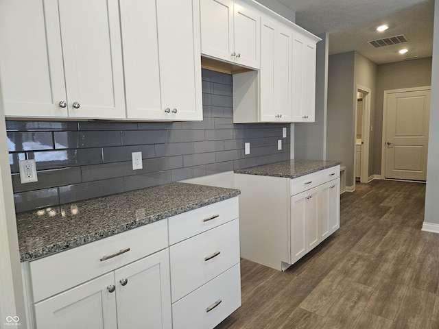 kitchen with decorative backsplash, white cabinets, dark hardwood / wood-style floors, and dark stone countertops