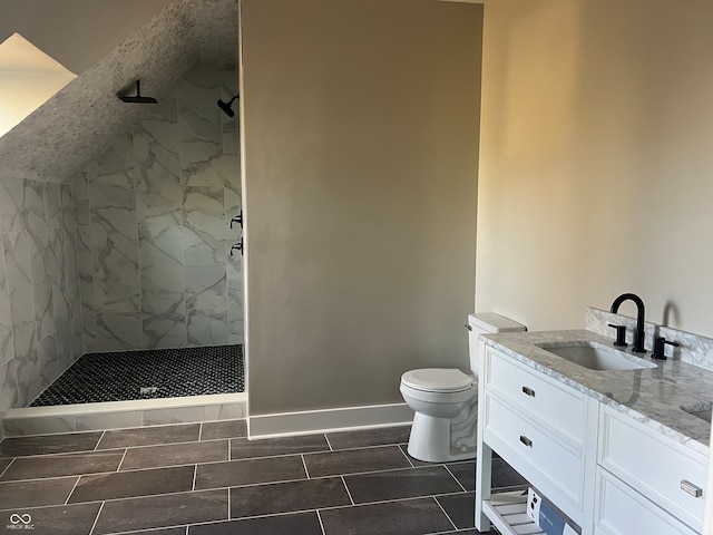 bathroom with toilet, vanity, and a tile shower