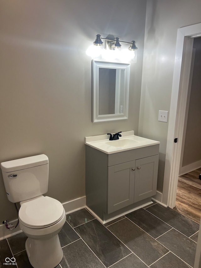 bathroom with hardwood / wood-style flooring, vanity, and toilet