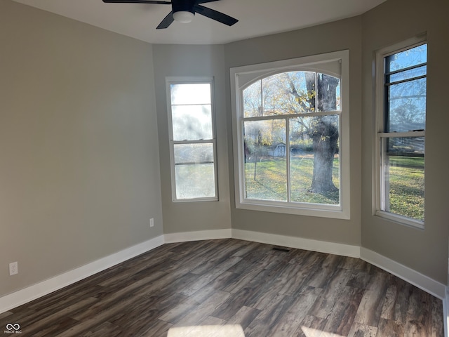 spare room with dark wood-type flooring, a healthy amount of sunlight, and ceiling fan