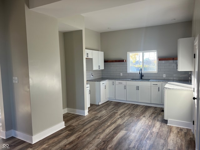 kitchen featuring tasteful backsplash, light stone counters, white cabinetry, dark hardwood / wood-style floors, and sink