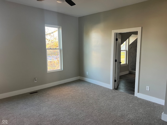 unfurnished room with dark colored carpet and ceiling fan