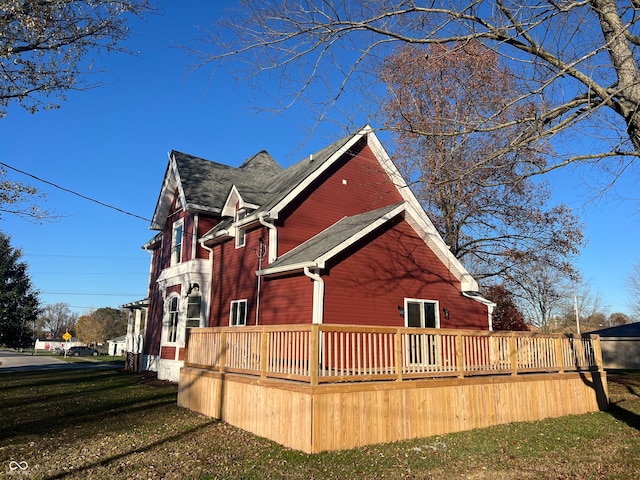 view of side of property featuring a lawn and a wooden deck