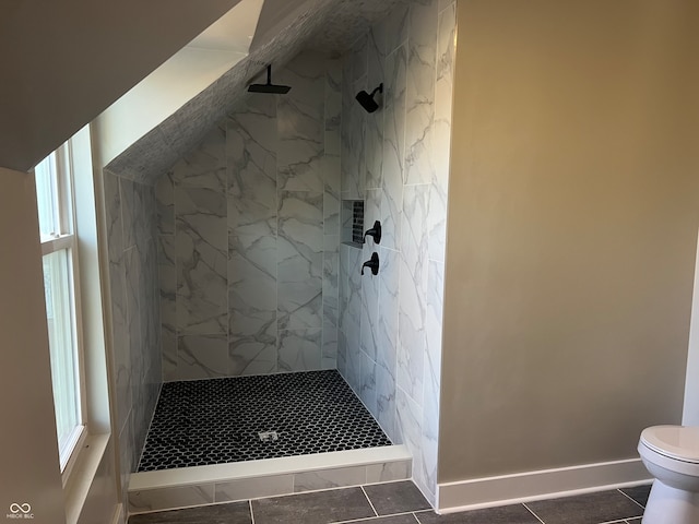 bathroom with tiled shower, a healthy amount of sunlight, and tile patterned floors