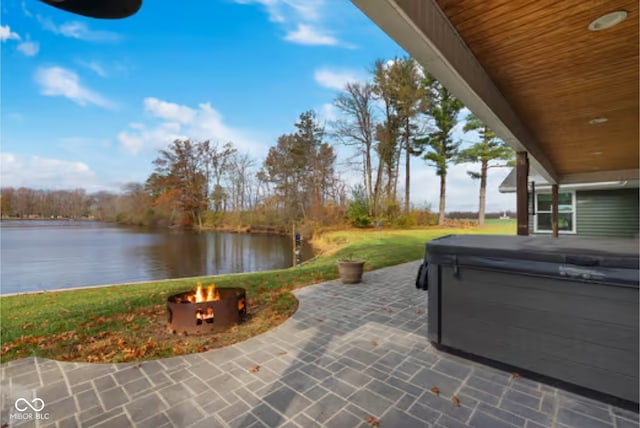 view of patio / terrace with a water view, a hot tub, and a fire pit