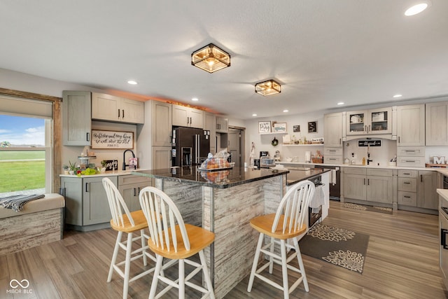 kitchen with a kitchen breakfast bar, light hardwood / wood-style flooring, dark stone countertops, appliances with stainless steel finishes, and a kitchen island