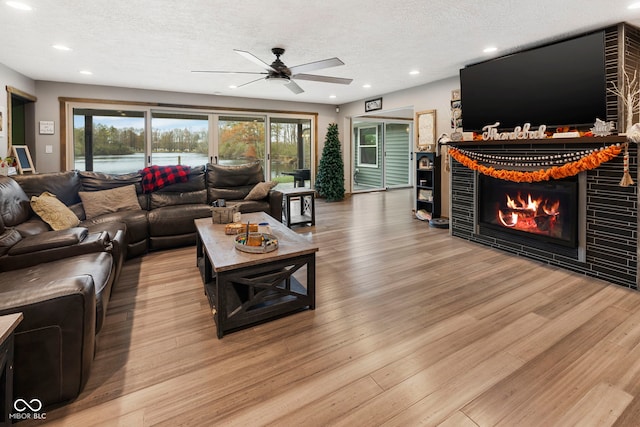 living room with a textured ceiling, light wood-type flooring, plenty of natural light, and ceiling fan