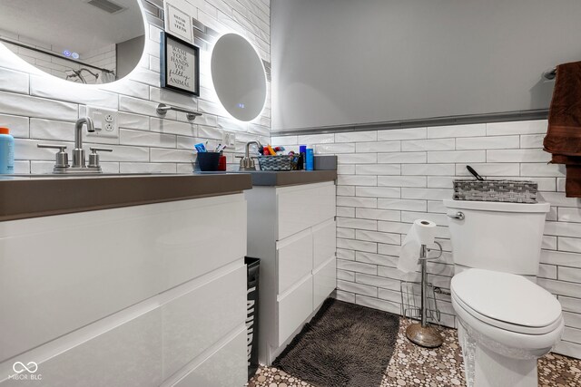 bathroom featuring vanity, toilet, and tile walls