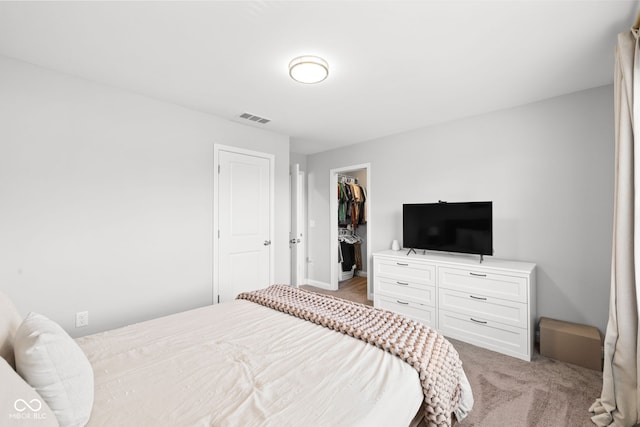 bedroom with light colored carpet, a closet, and a walk in closet