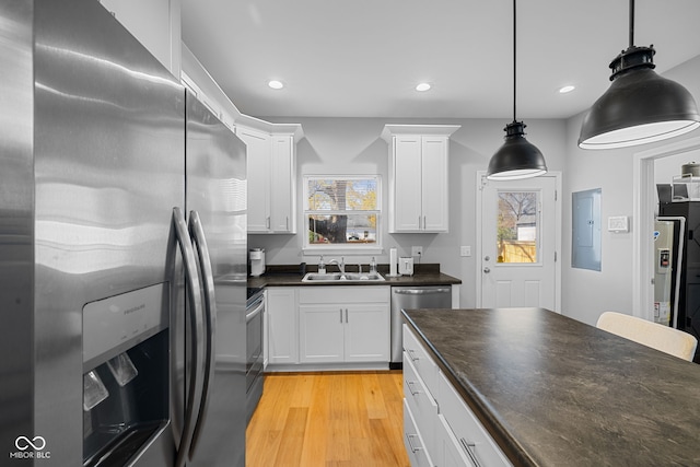 kitchen featuring white cabinets, light hardwood / wood-style floors, decorative light fixtures, and appliances with stainless steel finishes