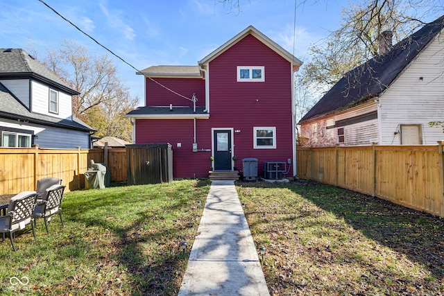 rear view of property with cooling unit and a yard