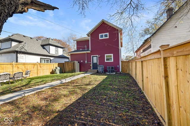 rear view of house featuring a lawn and central AC