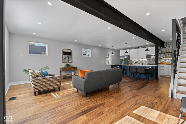 1514 E 12th St, Indianapolis, IN 46201 - living area featuring stairs, light wood-type flooring, recessed lighting, baseboards, and beamed ceiling