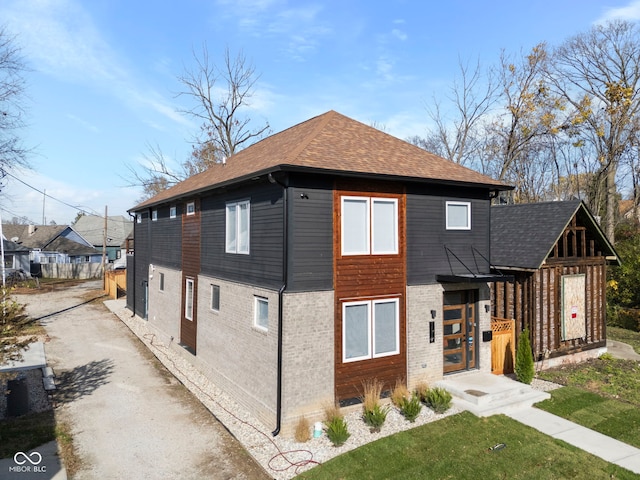 1514 E 12th St, Indianapolis, IN 46201 - view of side of home with a shingled roof, a yard, brick siding, and driveway