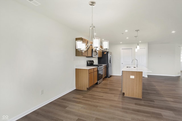 kitchen with appliances with stainless steel finishes, dark hardwood / wood-style flooring, hanging light fixtures, sink, and a kitchen island with sink