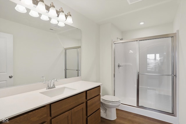 bathroom featuring hardwood / wood-style flooring, a shower with shower door, vanity, and toilet