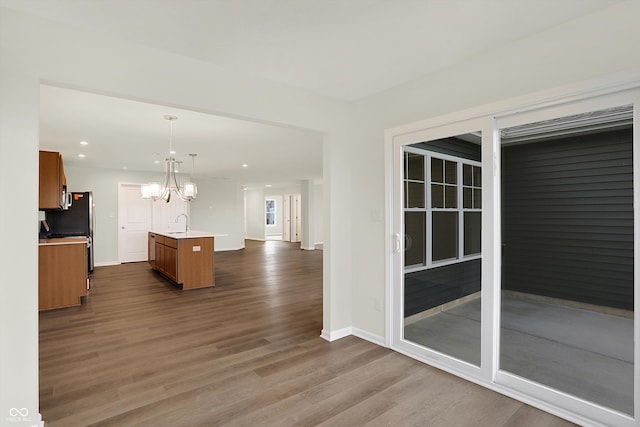 kitchen with dark hardwood / wood-style flooring, a notable chandelier, sink, a kitchen island with sink, and pendant lighting