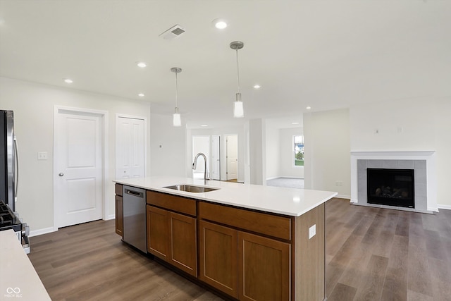 kitchen featuring sink, appliances with stainless steel finishes, a fireplace, pendant lighting, and dark hardwood / wood-style flooring