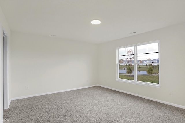 carpeted empty room featuring a water view