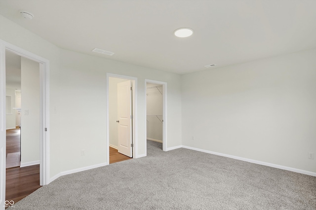 unfurnished bedroom featuring dark colored carpet, a closet, and a spacious closet