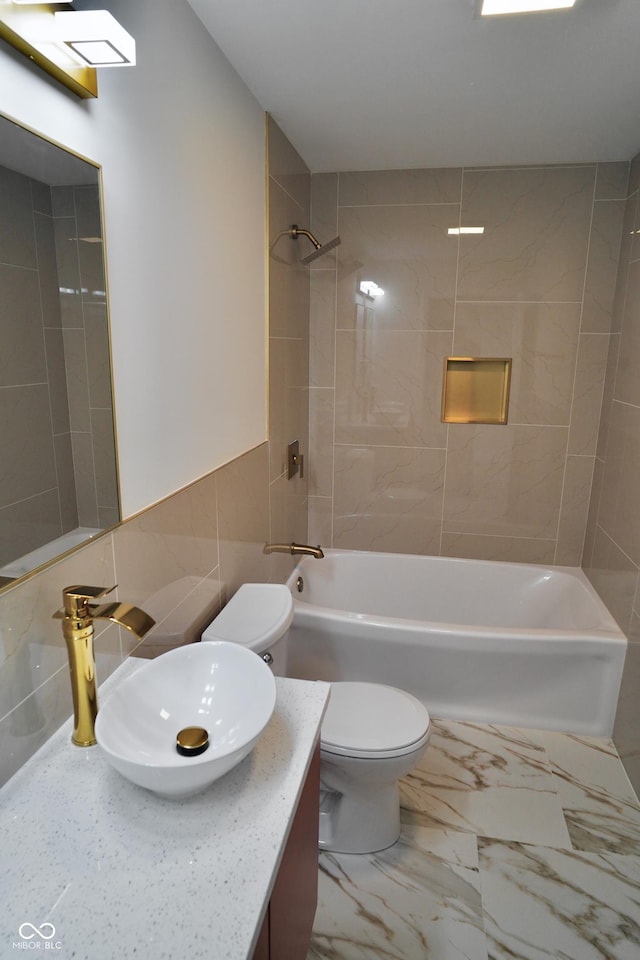 full bathroom featuring vanity, toilet, tile walls, and tiled shower / bath