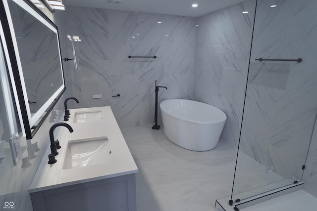 bathroom featuring a washtub, tile walls, and vanity