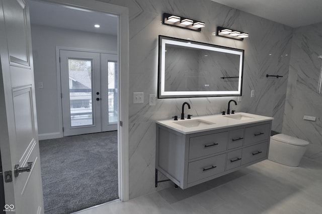 bathroom with vanity, toilet, and tile walls