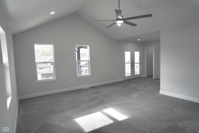 empty room with dark colored carpet, ceiling fan, lofted ceiling, and a wealth of natural light