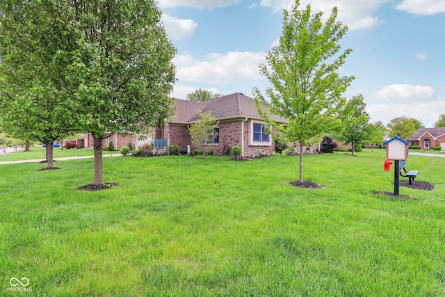 ranch-style home featuring brick siding, roof with shingles, and a front yard