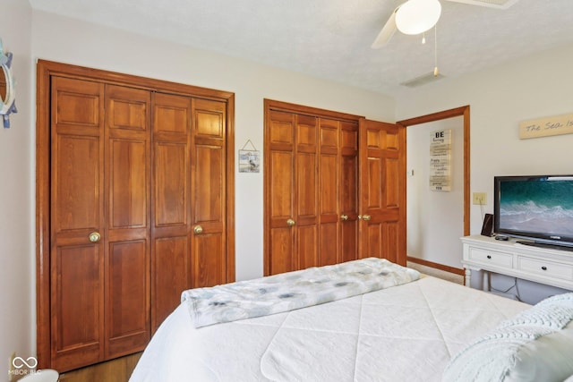 bedroom featuring two closets, baseboards, and ceiling fan
