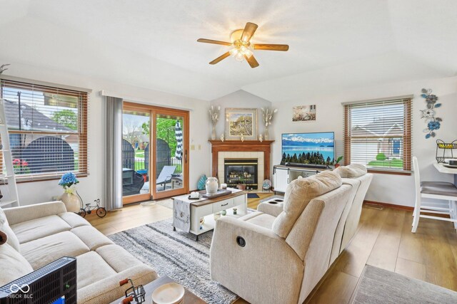 living room featuring a tile fireplace, light wood-style floors, lofted ceiling, and ceiling fan