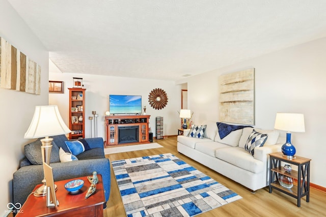 living room featuring baseboards, a fireplace, and wood finished floors