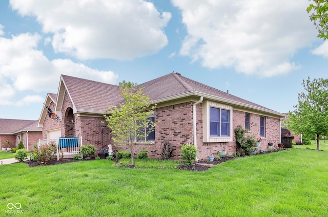 view of side of home featuring an attached garage, a shingled roof, brick siding, and a yard