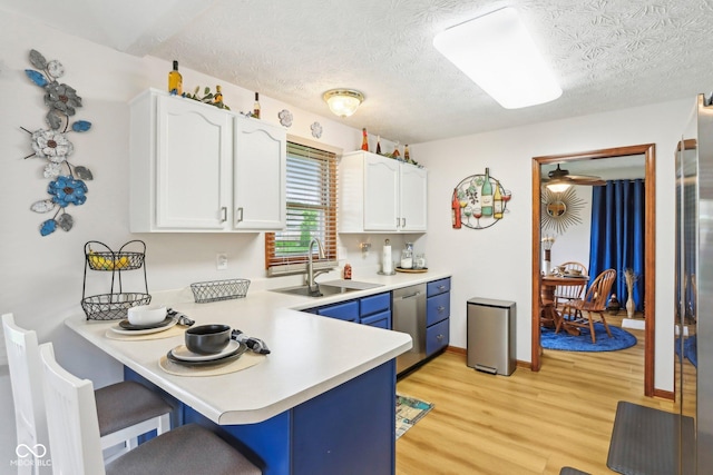 kitchen with a sink, blue cabinets, a breakfast bar area, light countertops, and white cabinets