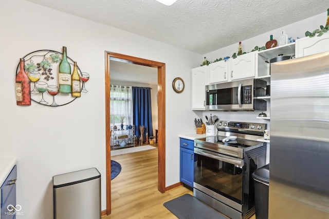 kitchen with appliances with stainless steel finishes, a textured ceiling, white cabinetry, light countertops, and light wood-style floors