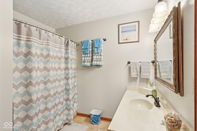 full bathroom featuring a shower with curtain, vanity, a textured ceiling, tile patterned floors, and baseboards