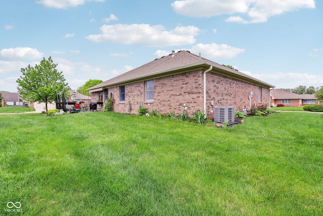 view of side of property with central AC unit, a yard, and brick siding