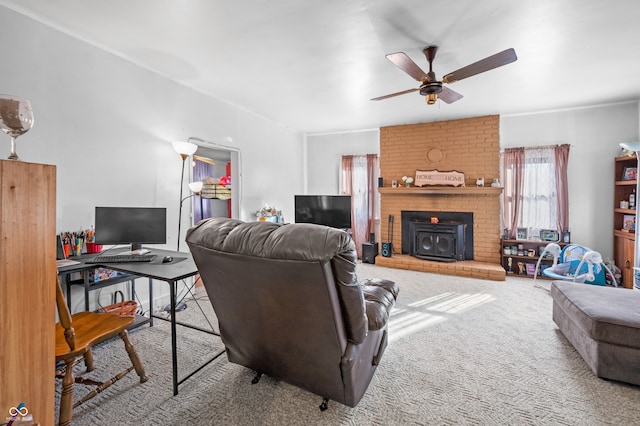 living room with ceiling fan, a wood stove, and carpet floors