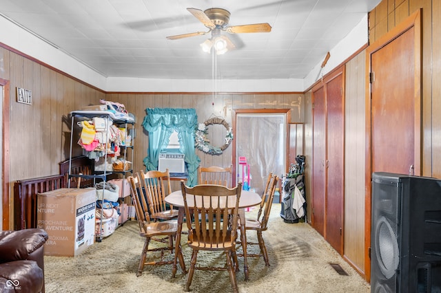 carpeted dining area featuring wooden walls, ceiling fan, and cooling unit