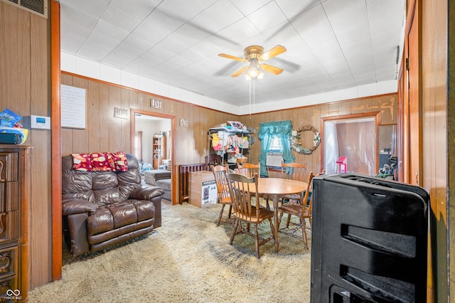 dining area with wooden walls, ceiling fan, heating unit, and carpet floors