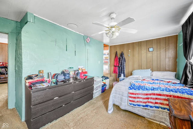 bedroom with carpet, ceiling fan, and wooden walls